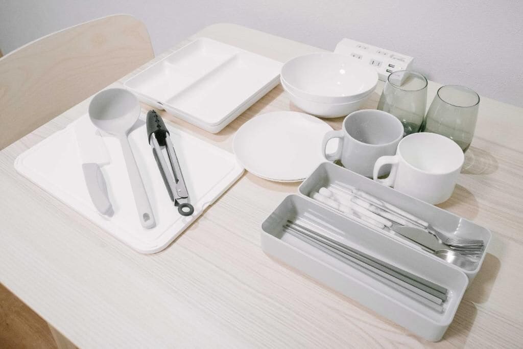 A neatly arranged table with white plates, bowls, cups, and cutlery.