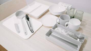 A neatly arranged table with white plates, bowls, cups, and cutlery.