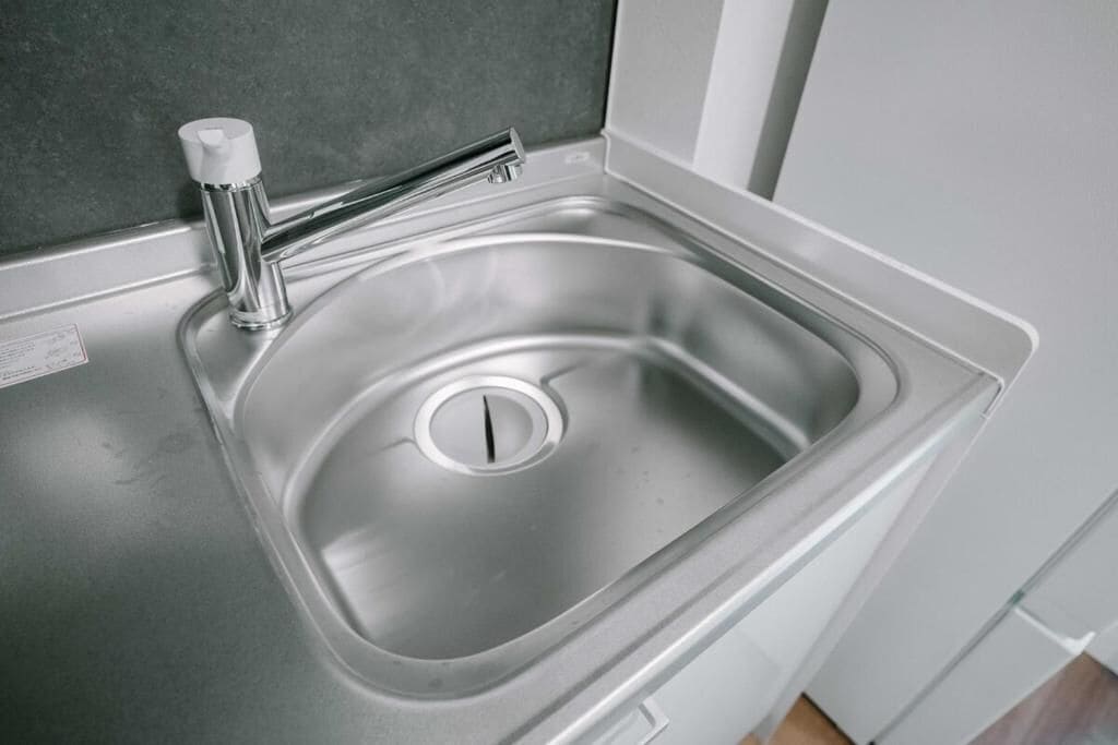 A stainless steel kitchen sink with a faucet and a drain.