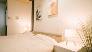 Une chambre d’hôtel comprenant un lit, une table de chevet, une lampe et une œuvre d’art accrochée au mur.