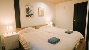 Un lit double avec deux serviettes bleues, une table de chevet avec une lampe et deux tableaux encadrés au mur.