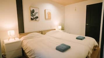 A double bed with two blue towels, a bedside table with a lamp, and two framed pictures on the wall.