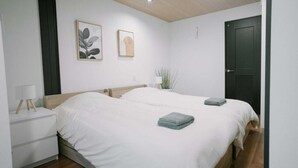 Une chambre avec deux lits, une table de chevet, une lampe et des œuvres d’art murales.