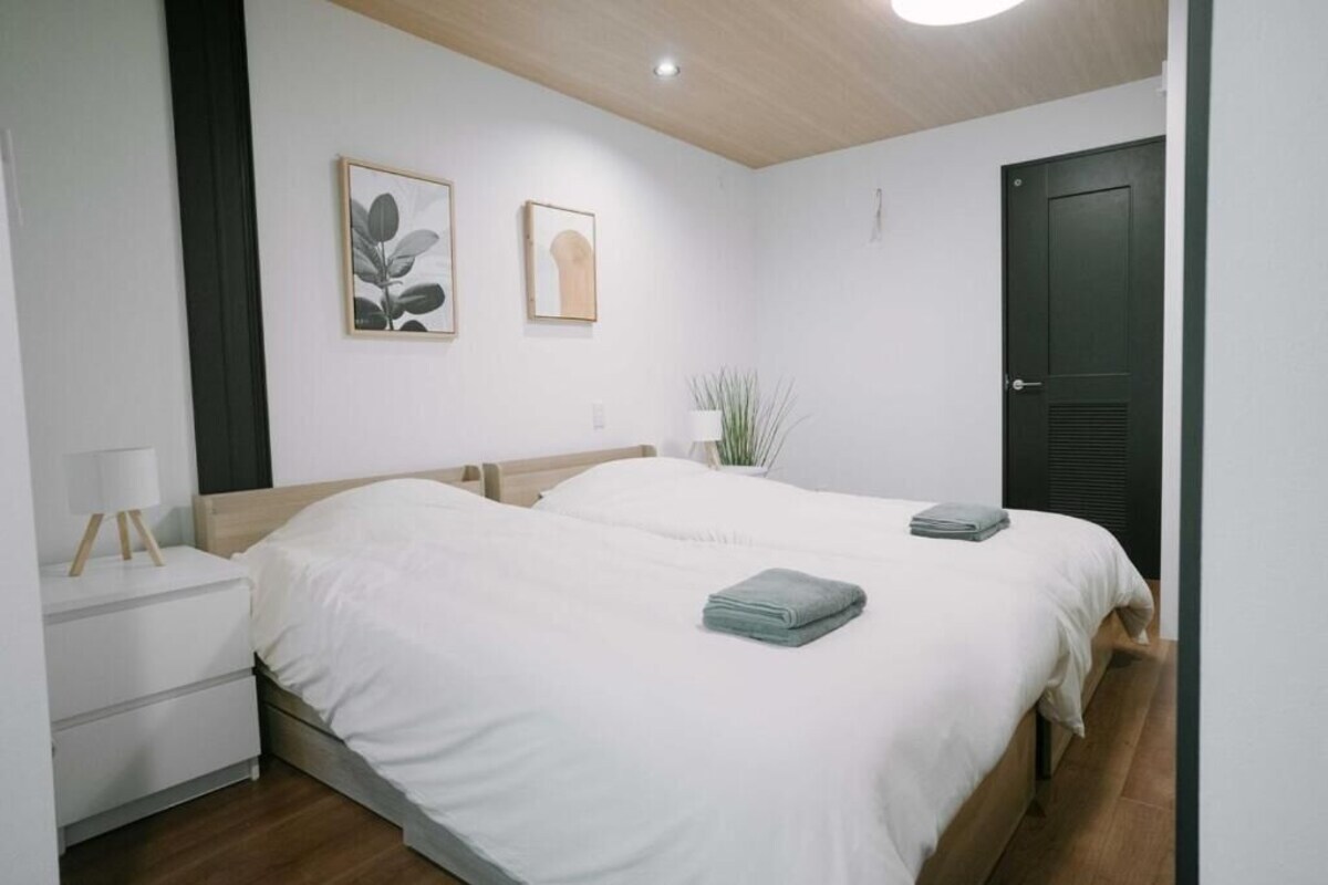 A bedroom with two beds, a bedside table, a lamp, and wall art.