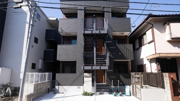 Un immeuble résidentiel à plusieurs étages, doté de balcons, d’une entrée sécurisée et d’un vélo garé à l’extérieur.