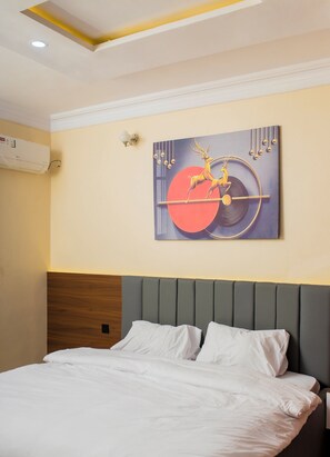 Ein Hotelzimmer mit einem Bett, einem Wandbild und einer Klimaanlage.