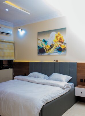 A modern bedroom with a bed, a nightstand, and a wall-mounted air conditioner. - Luxury 4-bedroom duplex with stylish interiors, comfort, Wi-Fi & 24/7 security. (Lagos)