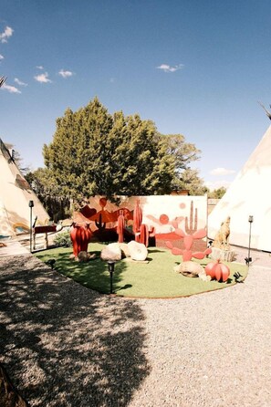 A desert-themed outdoor area with a cactus sculpture, a small structure, and a tent. - Luxurious Tipi with Insulated Comfort Near Ruidoso in Nogal, New Mexico (Nogal)