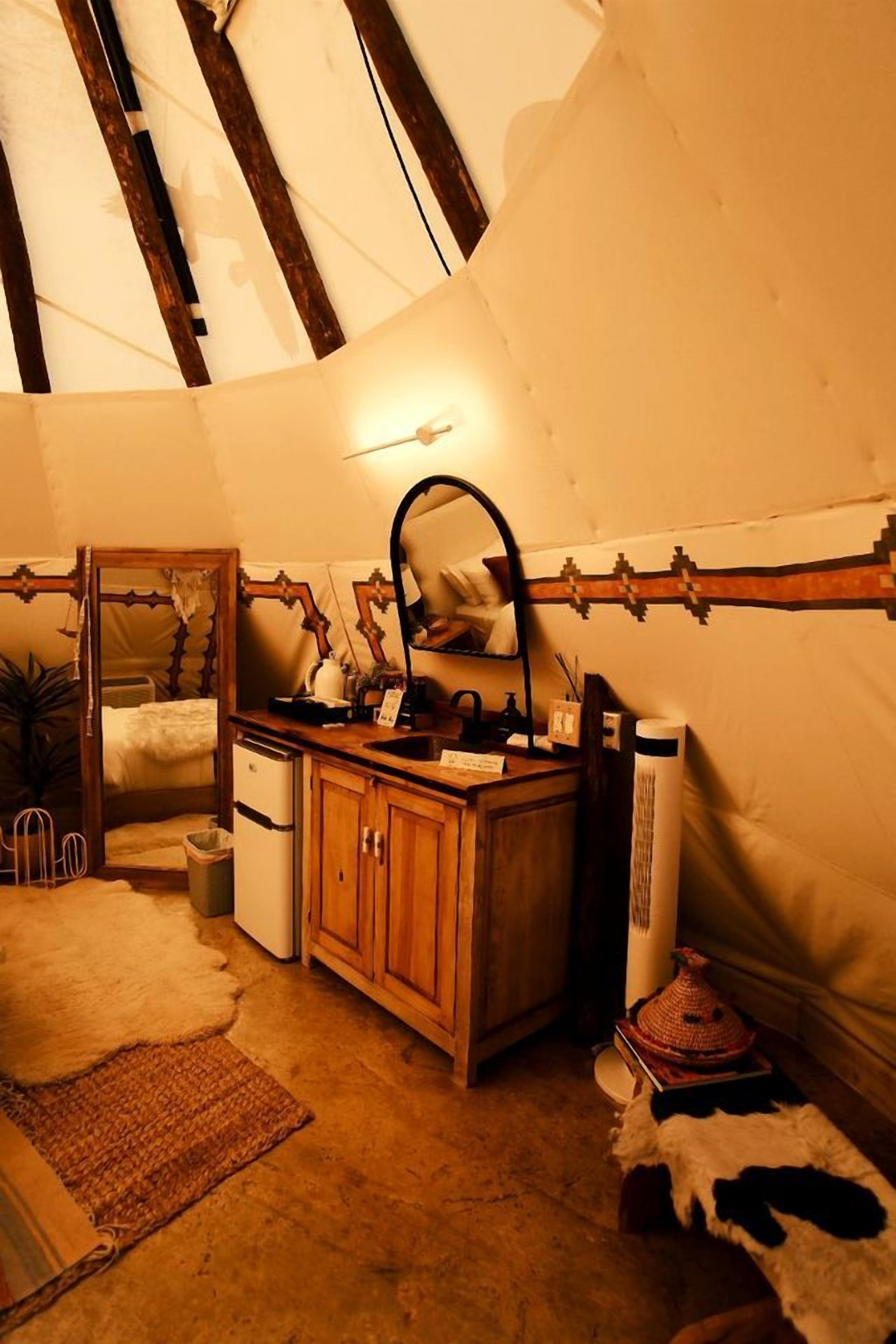 A cozy room with a wooden cabinet, a mirror, a small sink, and a cowhide rug.