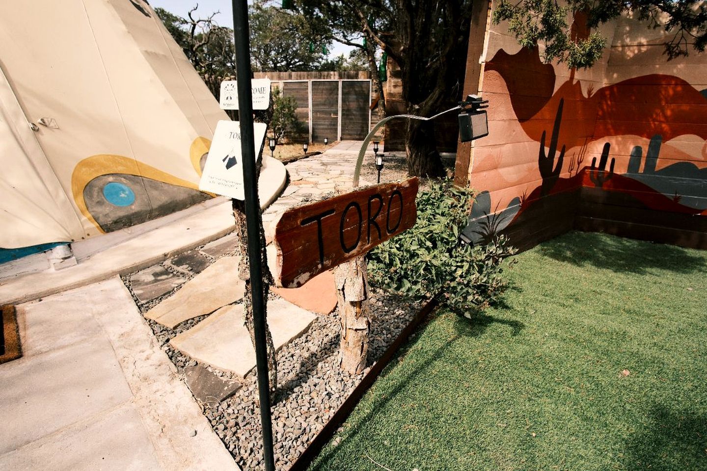 A sign labeled 'TORO' in a courtyard with artificial grass, a mural, and a water feature.