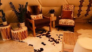 A tent-like room with a patterned wall, two chairs with cushions, a small table, and a cowhide rug.
