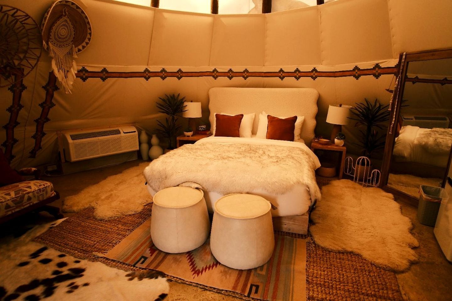 A spacious bedroom with a large bed, two bedside tables, a mirror, and a decorative headboard.