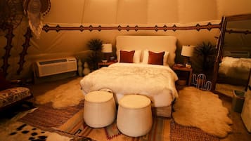 A spacious bedroom with a large bed, two bedside tables, a mirror, and a decorative headboard.