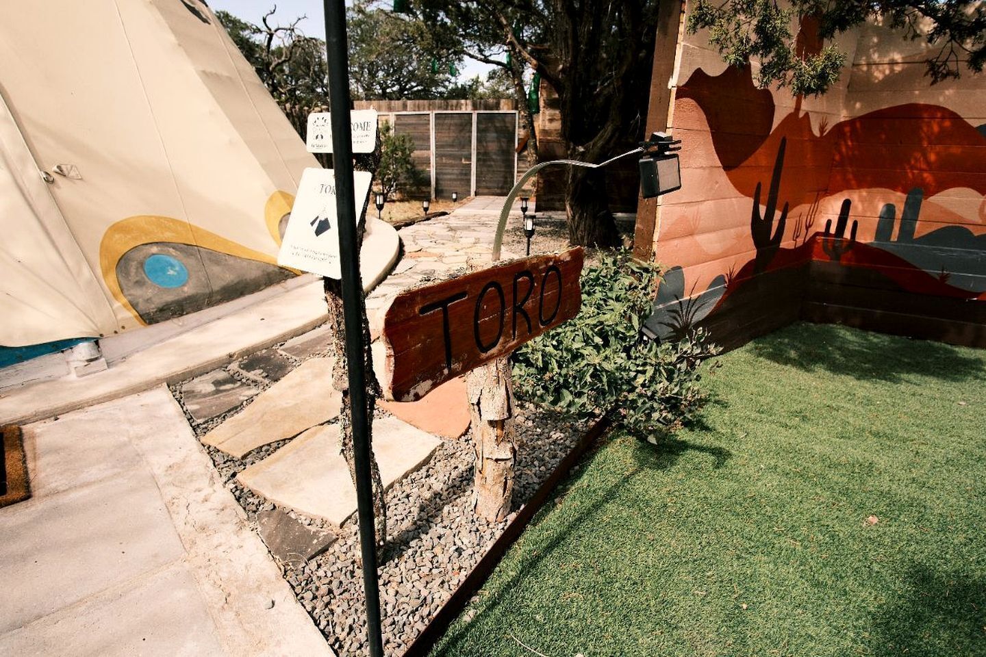 A sign labeled 'TORO' in a courtyard with artificial grass, a mural, and a water feature.