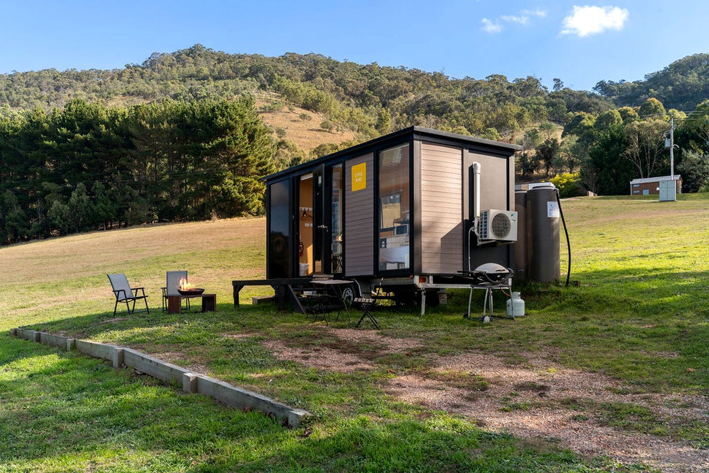 A small cabin with a fire pit, outdoor seating, and a portable generator.