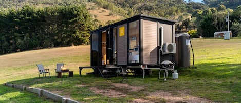 A small cabin with a fire pit, outdoor seating, and a portable generator.