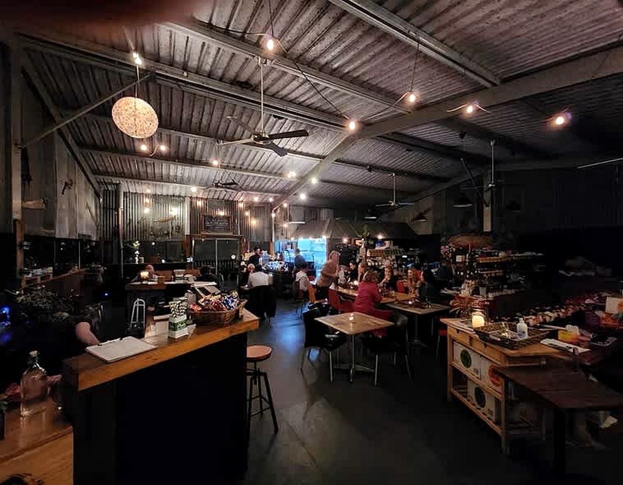 An indoor space with tables and chairs, a bar area, and a ceiling with exposed beams and lighting fixtures.
