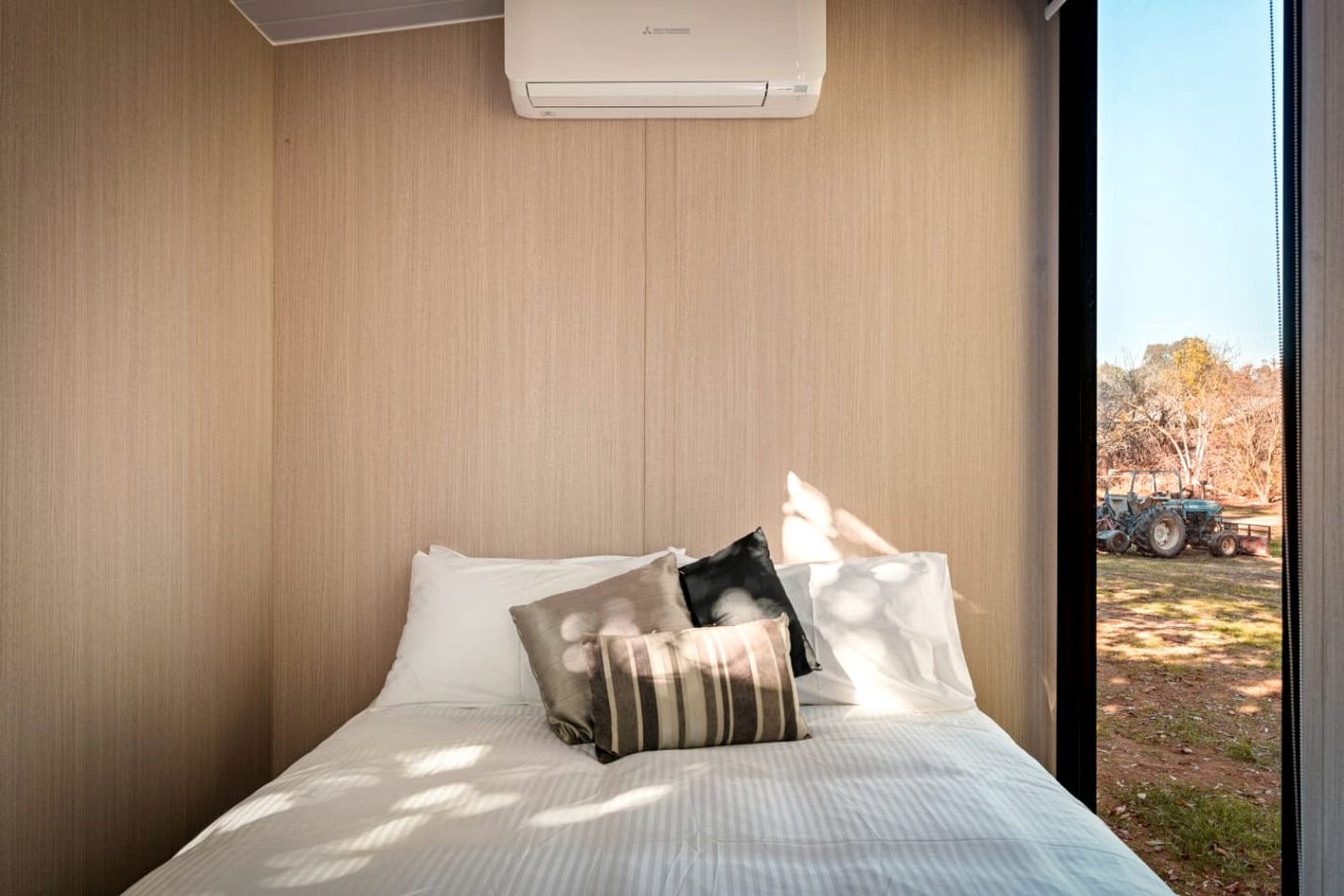 Une chambre à coucher avec un lit, des oreillers et un appareil de climatisation.