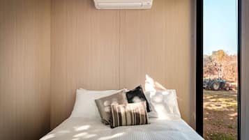 A bedroom with a bed, pillows, and an air conditioning unit.