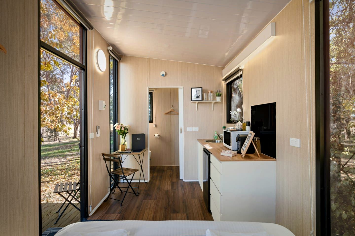 A compact room with a bed, a desk, and a kitchenette.