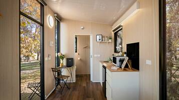 A compact room with a bed, a desk, and a kitchenette.