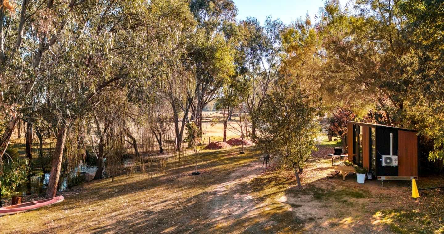 A campsite with a small wooden structure, a canoe, and a tent.