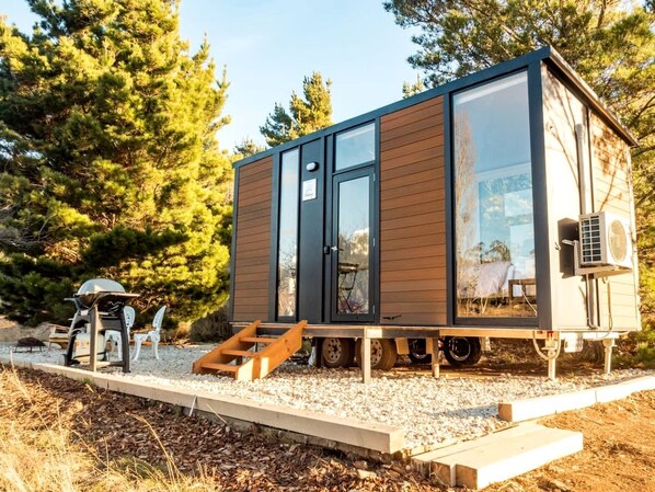A small, modern cabin with a sliding door, a large window, and a small porch area.
