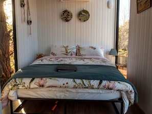 A bed with floral bedding, a bedside lamp, and wall decor.