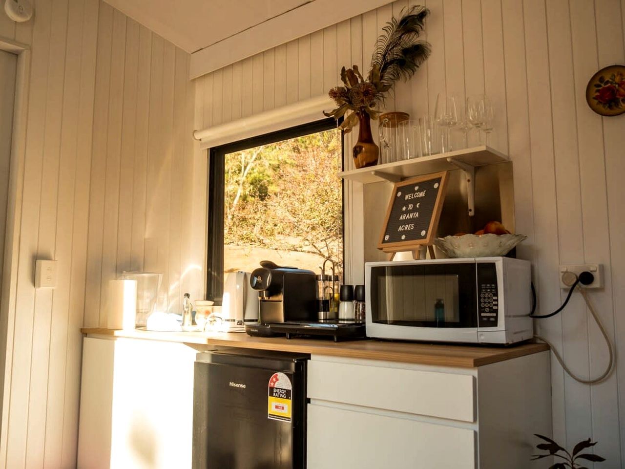 Eine kleine Küche mit einer Mikrowelle, einer Kaffeemaschine und einem Kühlschrank.