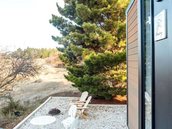 A patio with a chair and a fire pit, surrounded by gravel and a small tree.