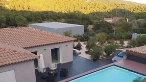 A modern house with a swimming pool, outdoor furniture, and a view of a forested hill. - Separate master bedroom (Bandol)