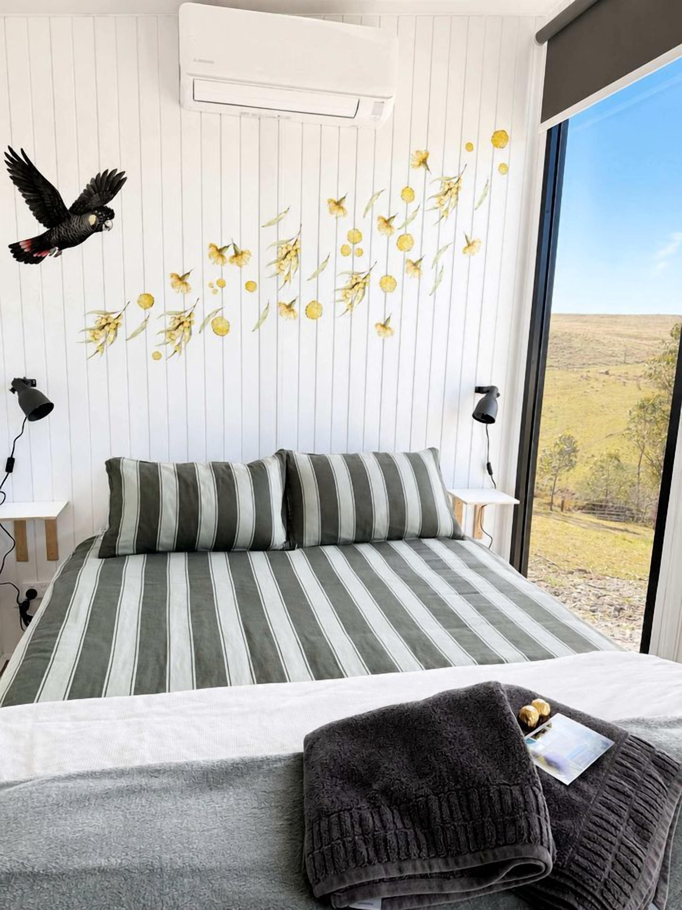 Un dormitorio con una cama grande, una ventana con vistas y aire acondicionado de pared.