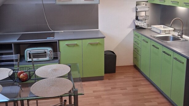 A compact kitchen with green cabinets, a stainless steel sink, and a built-in oven.
