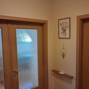 Een houten deur met een matglazen ruit, een decoratief object aan de muur en een klein houten plankje.