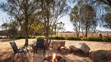 An outdoor seating area with two chairs and a fire pit surrounded by rocks.