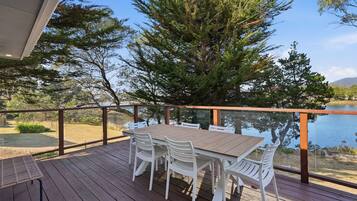 A wooden deck with a table and chairs overlooking a body of water.