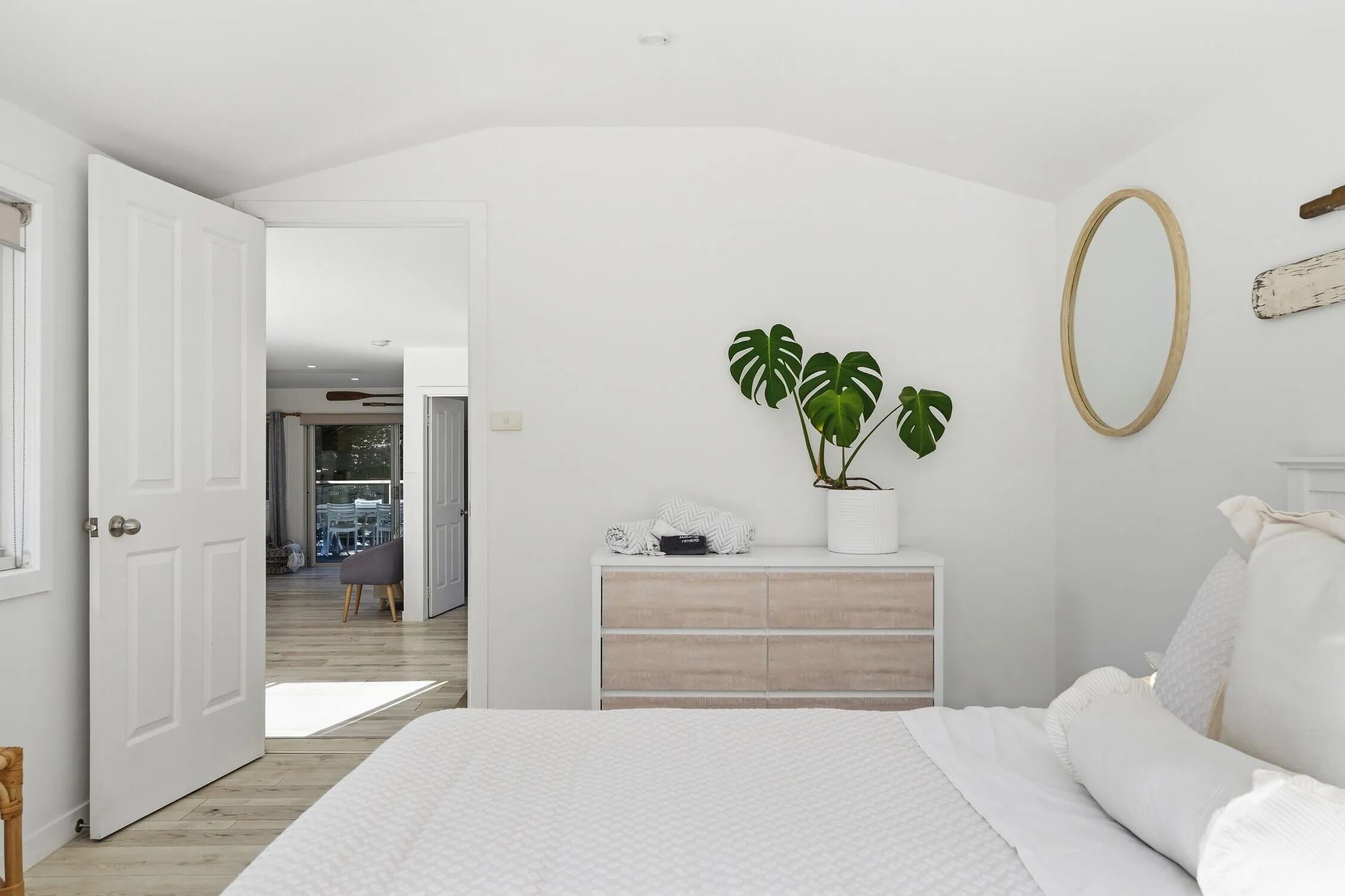 Un dormitorio con cama, cómoda, planta en maceta y espejo.