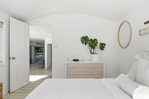 A bedroom with a bed, a dresser, a potted plant, and a mirror. - Prosser River Retreat - Gateway to Maria Island (Orford)