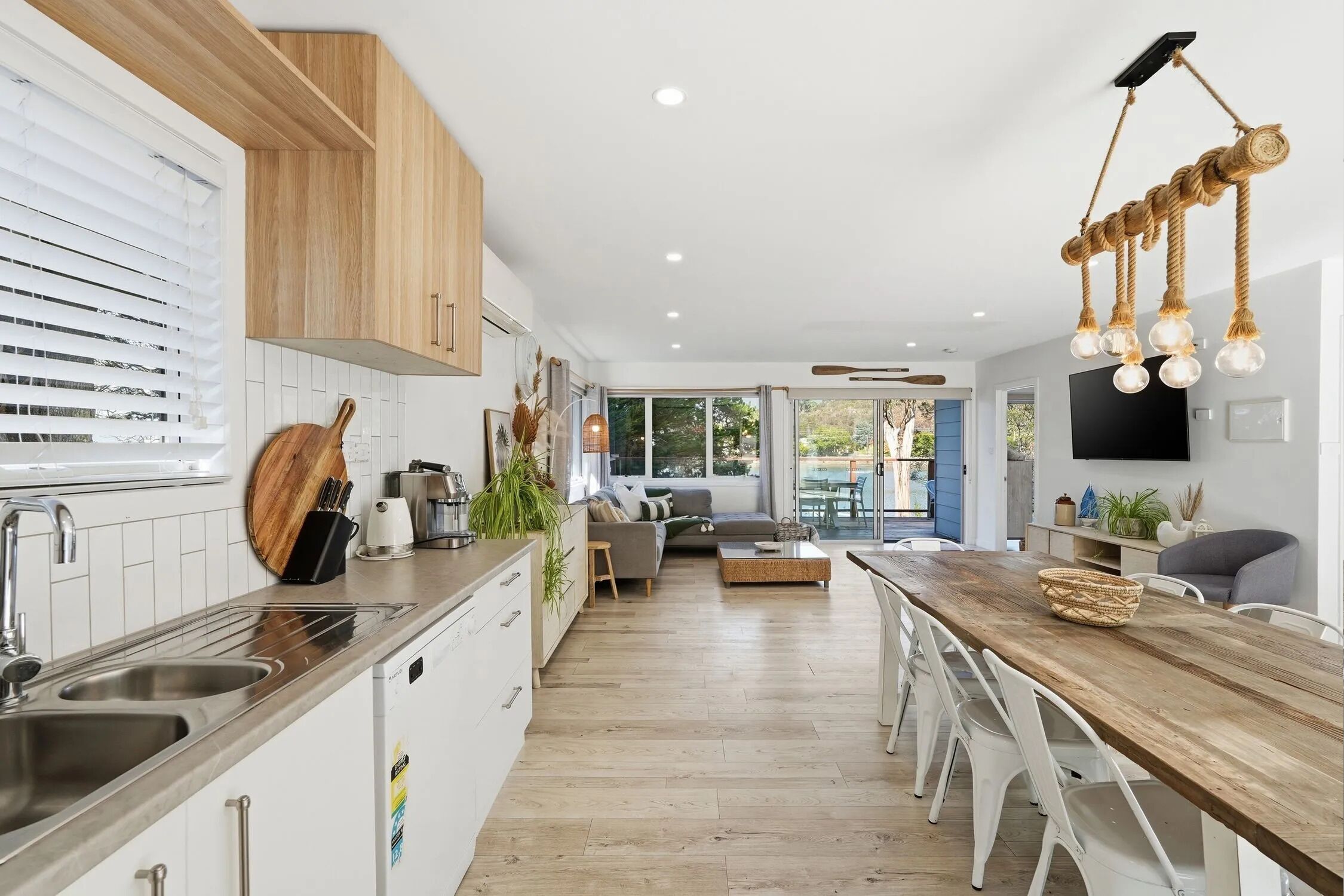 A modern kitchen with a wooden countertop, stainless steel sink, and a dining area with a wooden table and chairs.