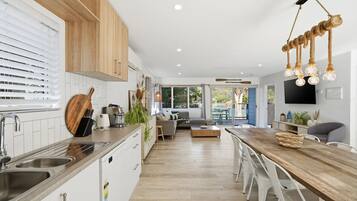A modern kitchen with a wooden countertop, stainless steel sink, and a dining area with a wooden table and chairs.
