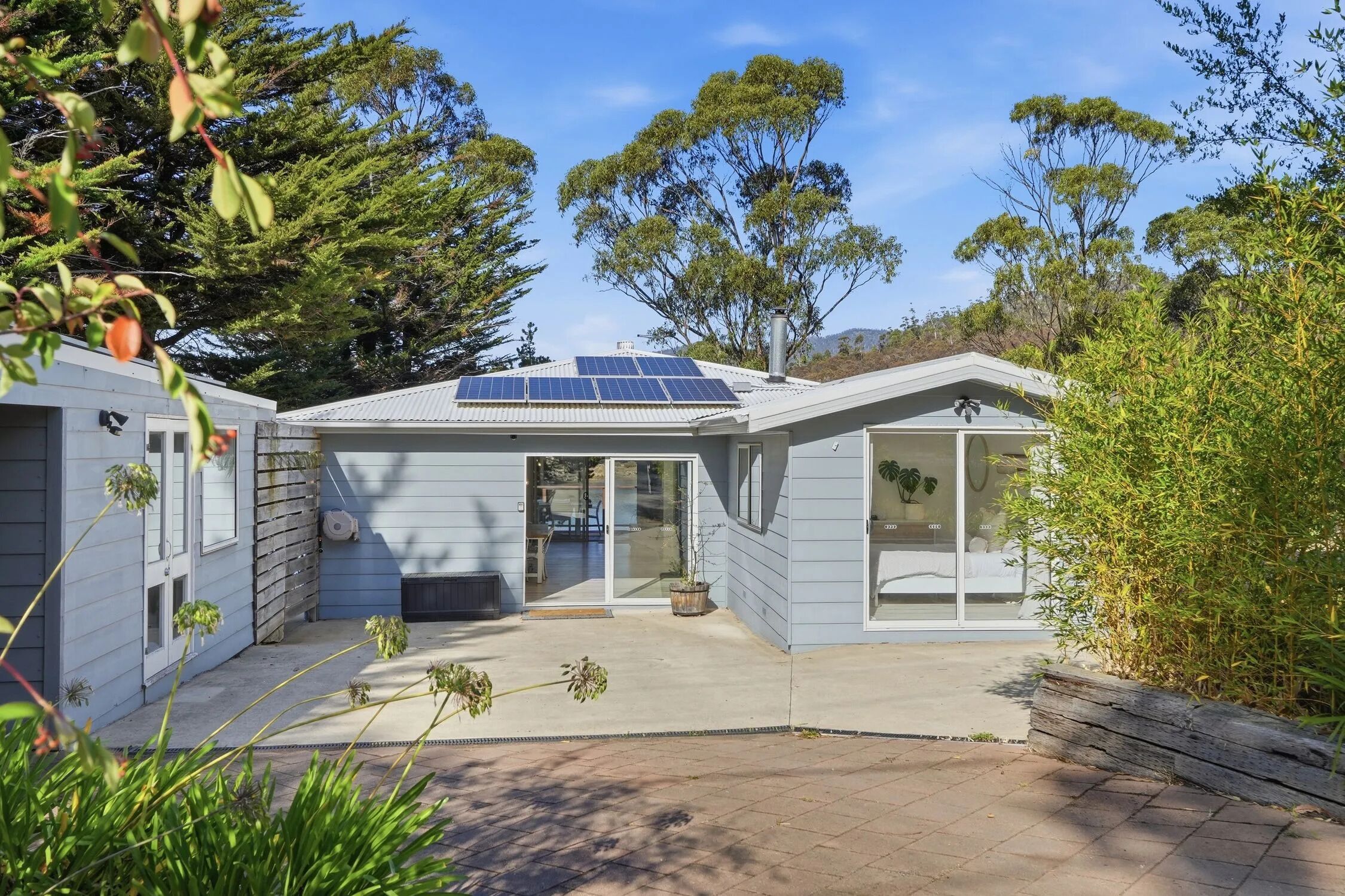A modern house with solar panels, a covered patio, and a garden.