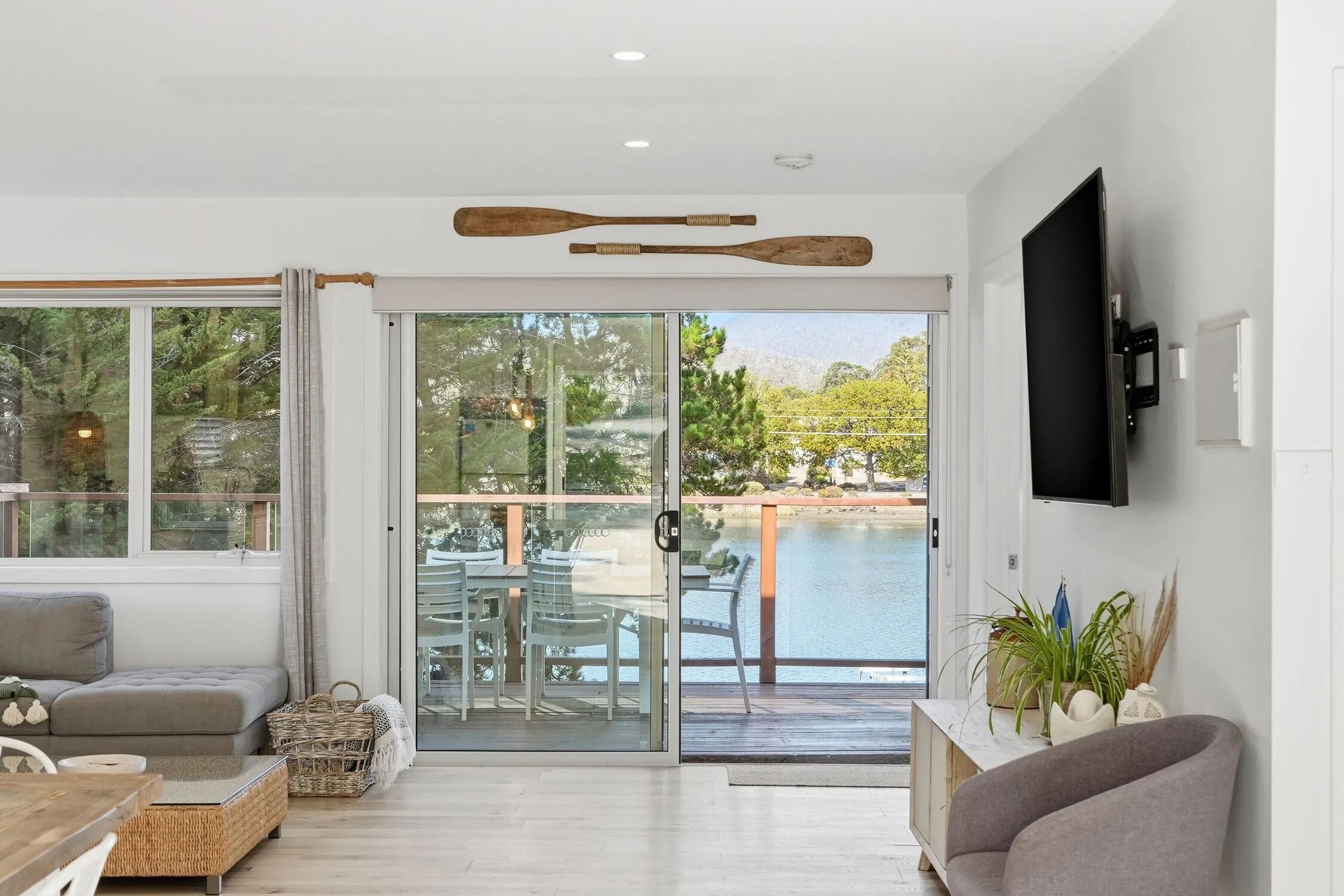 A modern living room with a sofa, dining table, and a view of a pool through glass doors.