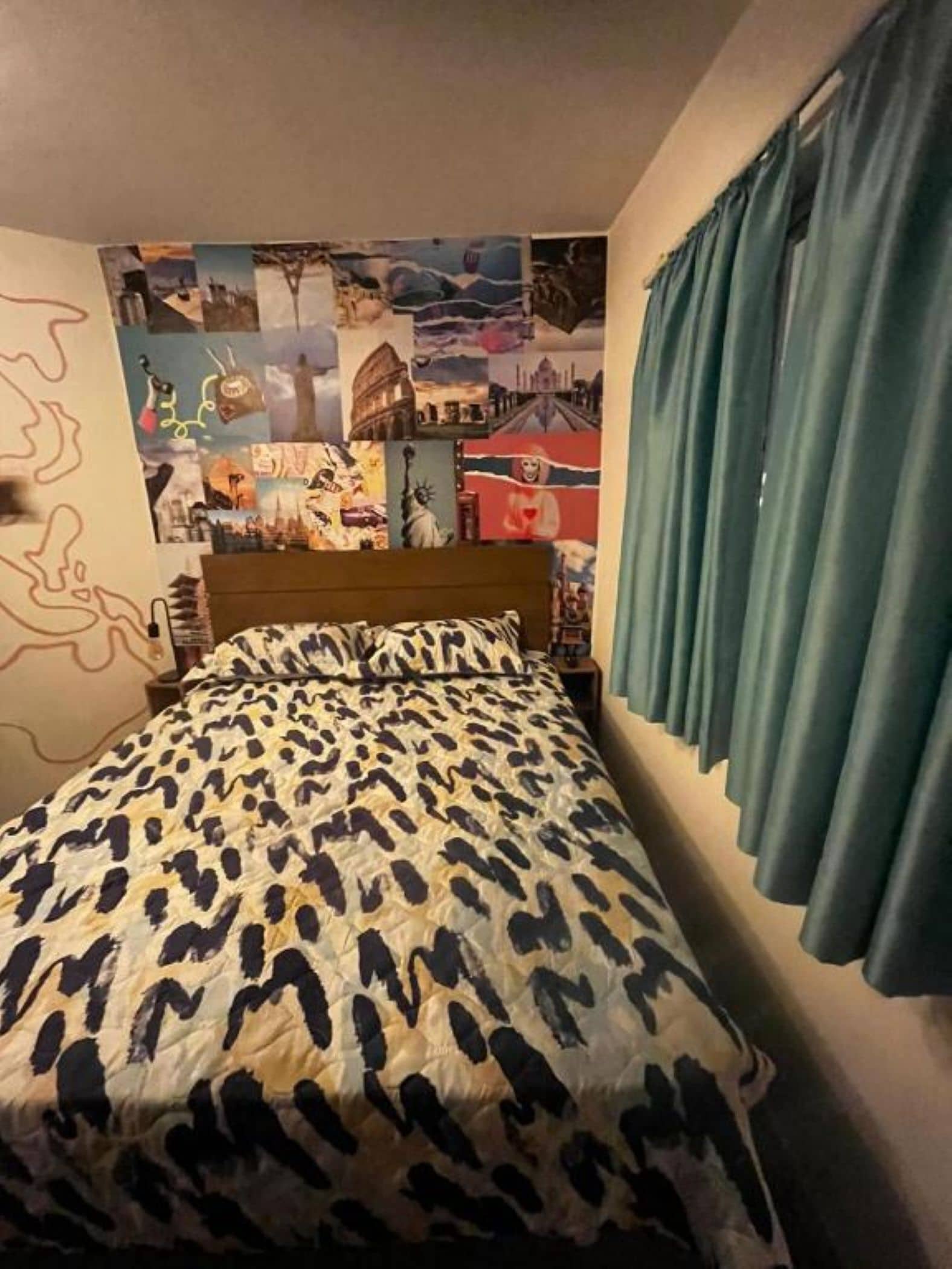 A bedroom with a bed, a wall with a collage of images, and a curtain.