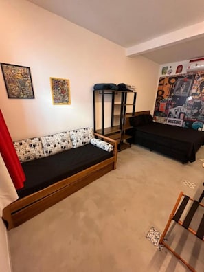 A room with a sofa, a bunk bed, and a wall with posters.