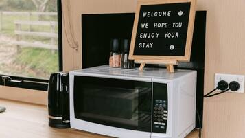 A microwave oven with a small wooden sign on top displaying a welcome message.
