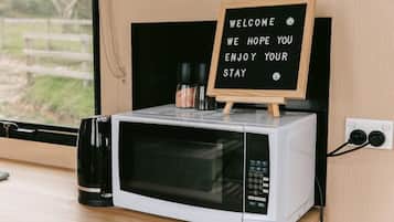 Un horno microondas con un pequeño letrero de madera encima que muestra un mensaje de bienvenida.