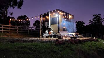 A small, single-story building with a porch, outdoor seating, and a grill area.