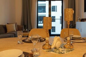 A dining table set with glasses, plates, and a decorative golden candelabra. - bnbme - La Cote 3 - 1BR (Dubai)