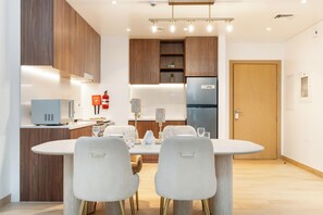 Una cocina moderna con armarios de madera, microondas integrado y refrigerador de acero inoxidable.