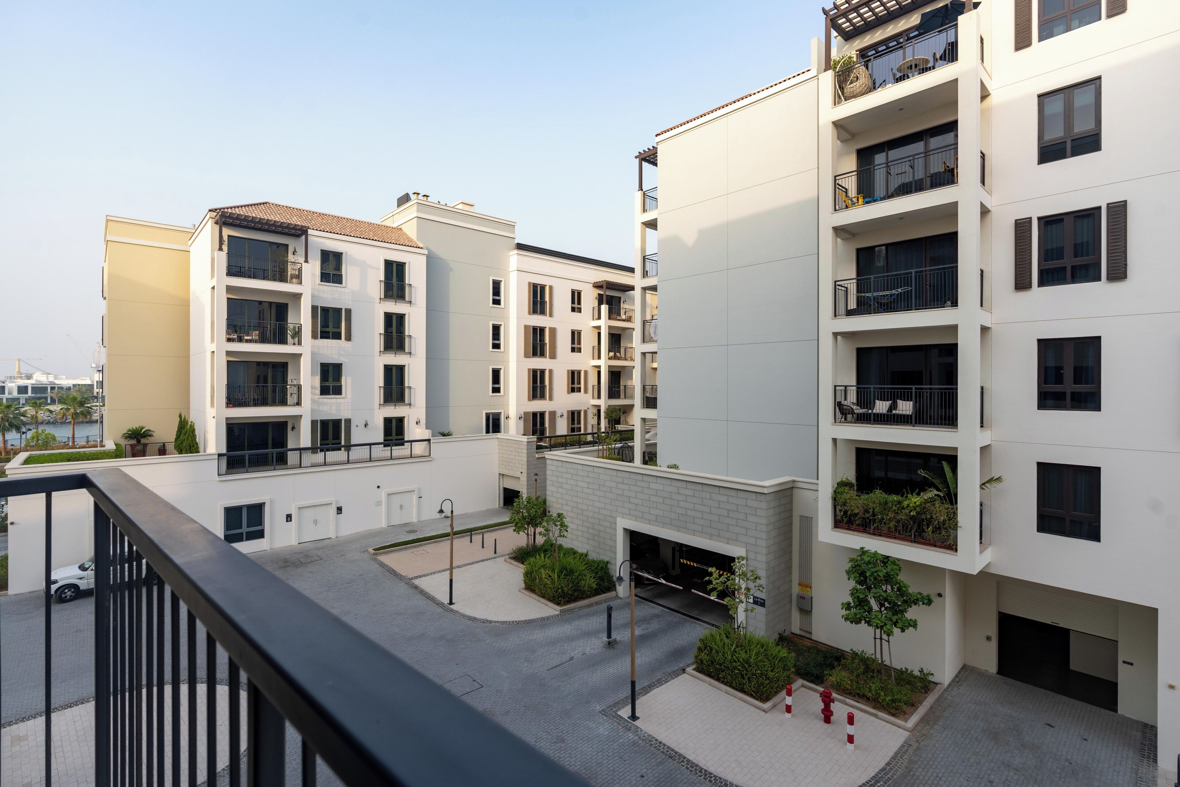 A multi-story residential building with balconies, a covered parking area, and a landscaped courtyard.